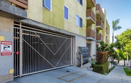 A gated entrance to a residential building with a warning sign.