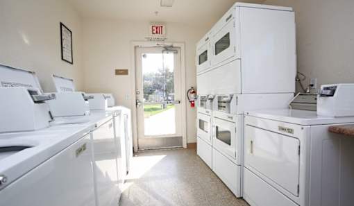 a kitchen with white appliances and a exit sign