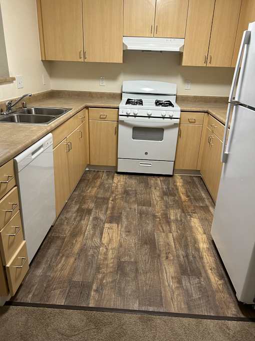 A kitchen with wooden cabinets and a stainless steel refrigerator.