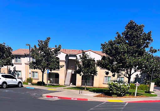 an apartment building with a parking lot and trees