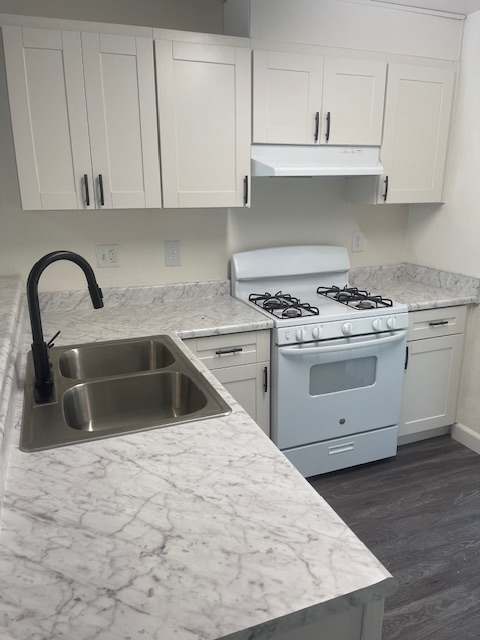 A kitchen with a marble countertop and white cabinets.