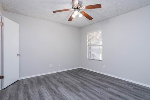 A room with a ceiling fan and a window with blinds.