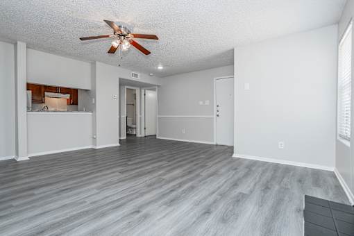 A room with a ceiling fan and wooden flooring.