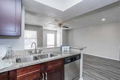 A kitchen with a sink, stove, and a fan.
