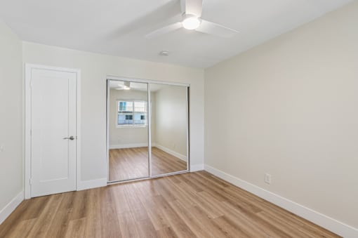A room with a white door and a mirror on the wall.