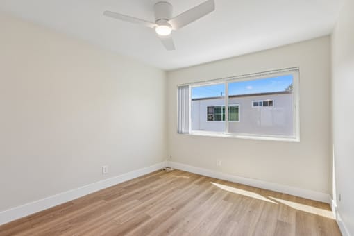 A room with a ceiling fan and a window with blinds.