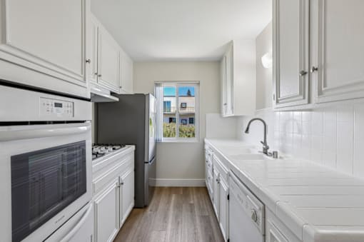 A kitchen with white cabinets and appliances.