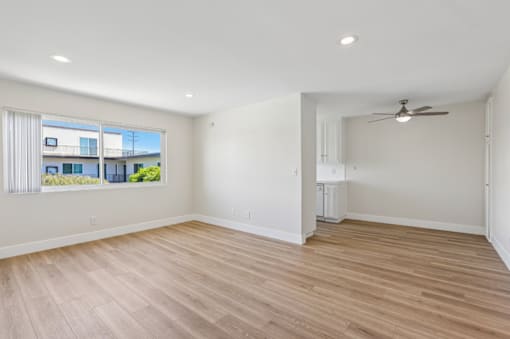 A spacious room with wooden flooring and a ceiling fan.