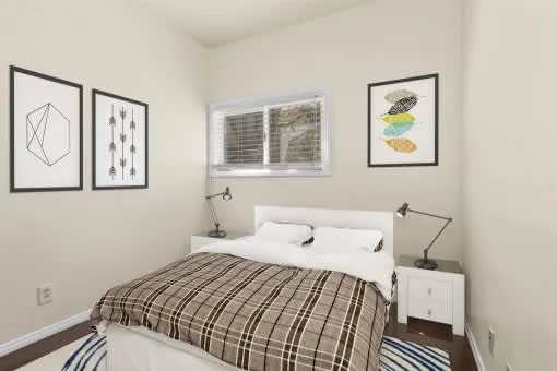A bedroom with a bed, nightstand, and three framed pictures on the wall.