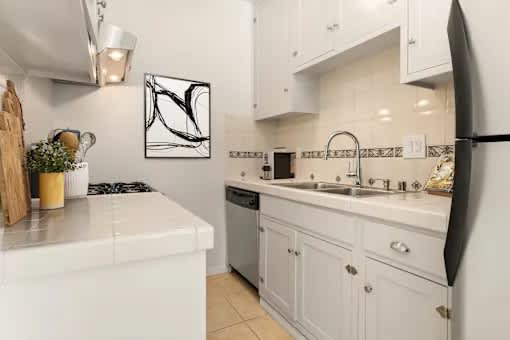A white kitchen with a black fridge and a white stove.