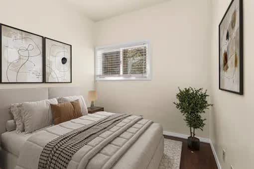 A bedroom with a large bed and a small tree on the side table.