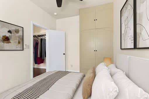 A bedroom with a bed, a wardrobe, and a ceiling fan.