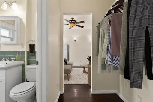 A bathroom with a toilet, sink, and a bed in the background.
