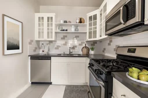 A modern kitchen with white cabinets and black appliances.