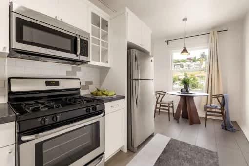 A modern kitchen with white appliances and a dining area with a table and chairs.
