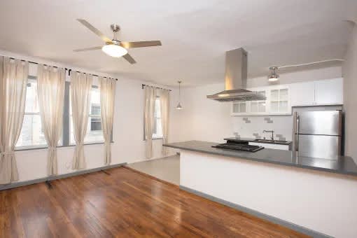 A kitchen with a wooden floor and a ceiling fan.
