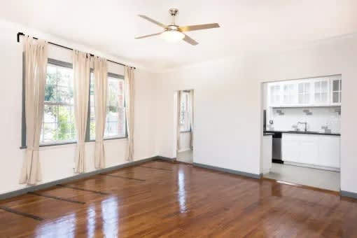A room with a ceiling fan and wooden floors.
