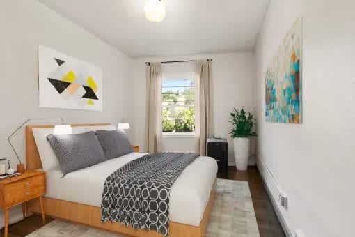 A bedroom with a bed, nightstand, and a painting on the wall.