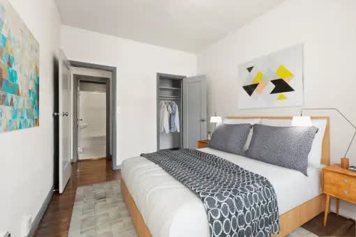 A bedroom with a bed, nightstand, and a painting on the wall.