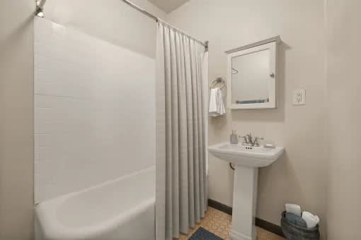 A white bathroom with a white sink and a white bathtub.