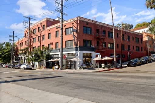 A street view of a red brick building with cars parked in front.
