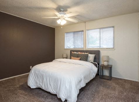 A bedroom with a bed, pillows, a nightstand, and a ceiling fan.