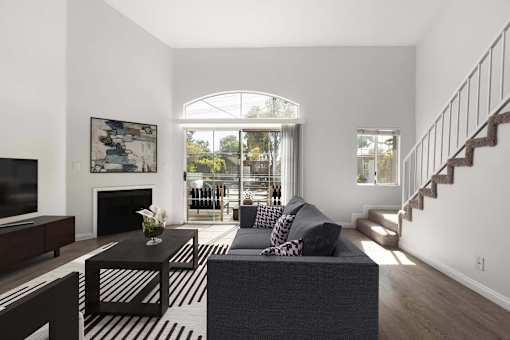 A living room with a grey couch and a black and white striped rug.