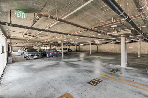 A parking garage with cars parked and an exit sign.