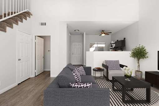 A living room with a grey couch and a black and white striped rug.