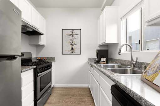 A modern kitchen with a stove, sink, and cabinets.