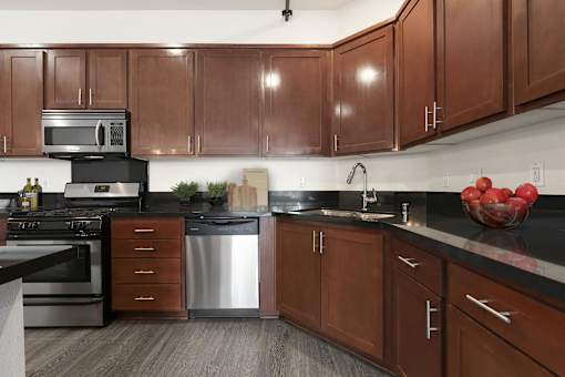 A kitchen with brown cabinets and a black countertop.