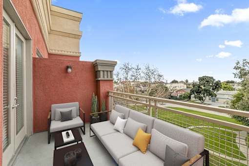 A balcony with a grey couch and a small table.