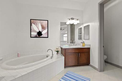 A white bathroom with a tub, sink, and mirror.