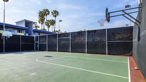 A basketball court with a basketball hoop and a fence surrounding it.
