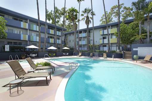 A swimming pool surrounded by lounge chairs and palm trees.