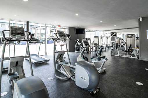 A gym with a variety of equipment including treadmills, stationary bikes, and weight machines.