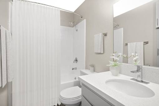 A white bathroom with a toilet, sink, and shower.