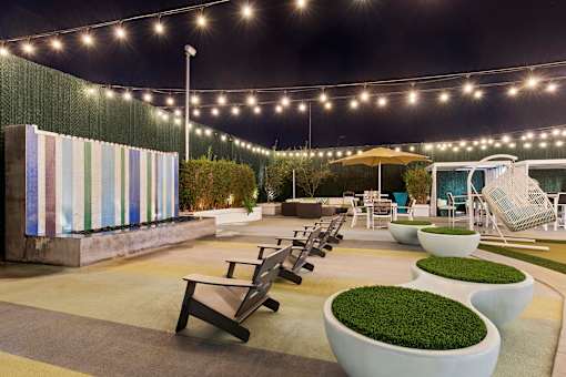 A patio area with tables, chairs, and a striped wall.