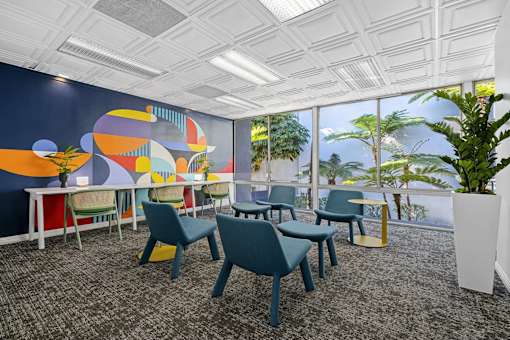 A room with a large mural on the wall and several chairs and tables.
