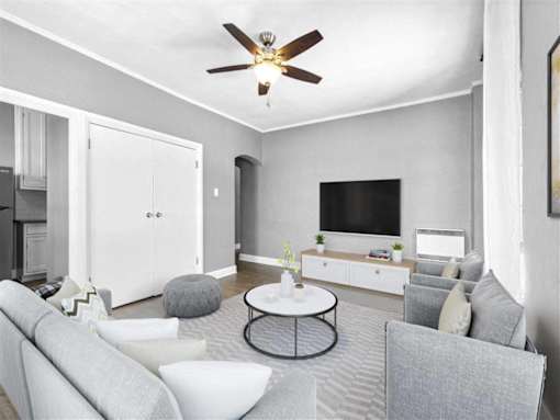 A living room with a grey couch, a white coffee table, and a ceiling fan.