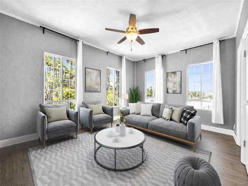 A living room with a grey couch, a coffee table, and a ceiling fan.