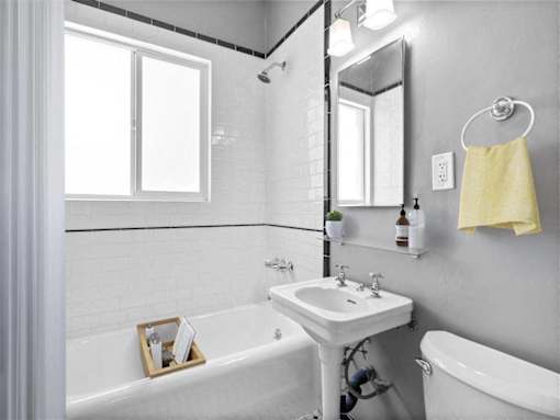 A white sink is in a bathroom with a white tub and a white toilet.