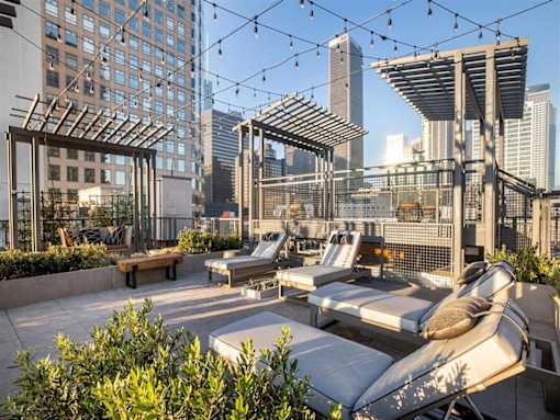 A rooftop patio with lounge chairs and a pergola.