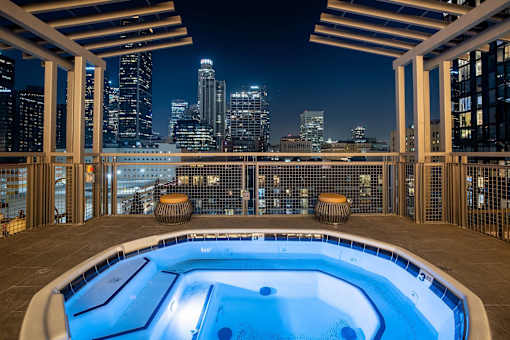 A hot tub on a rooftop with a city skyline at night in the background.