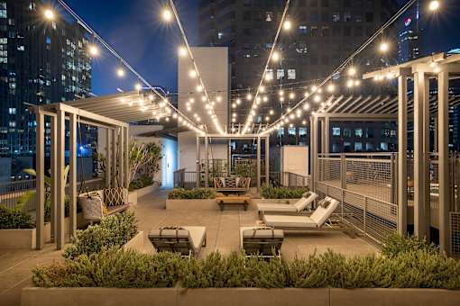 A rooftop patio with a white pergola and string lights.