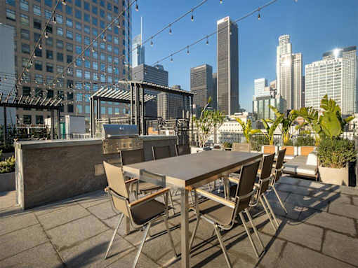 A table with chairs is set up on a rooftop with a city skyline in the background.