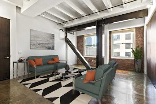 A living room with a green couch and a black and white rug.