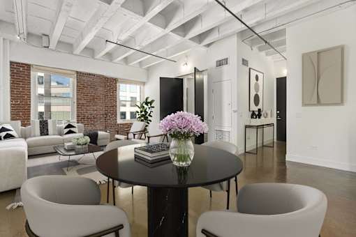 A modern living room with a black table and grey chairs.