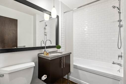 A white bathroom with a black vanity and a white bathtub.