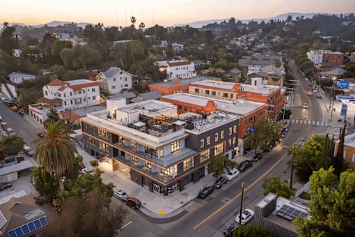 A sunset view of a street with cars and buildings.